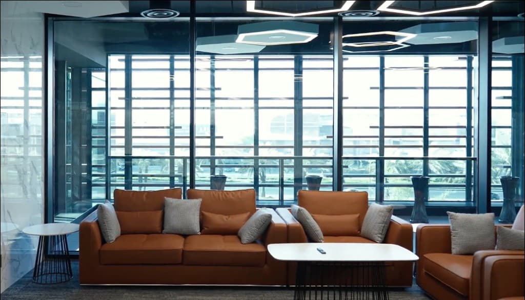 Corporate lounge with leather seating and glass wall overlooking palms