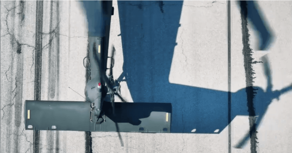 Top-down view of a helicopter tail rotor on a runway, long daylight shadow